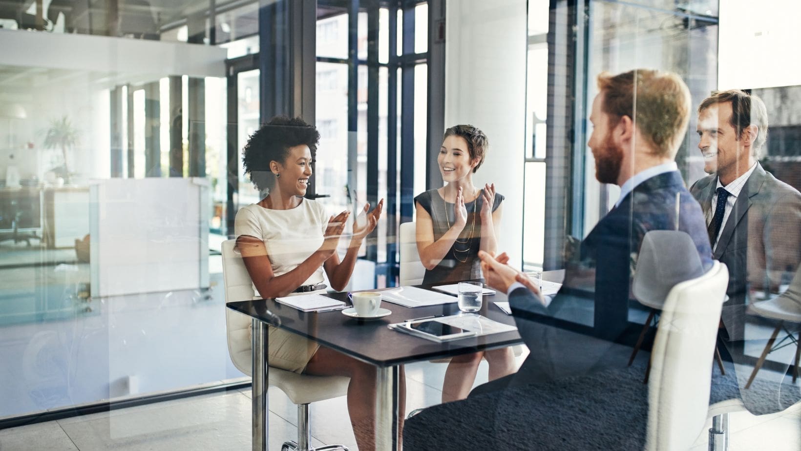 Adapt to different audiences- two women and two men at table smiling in a meeting