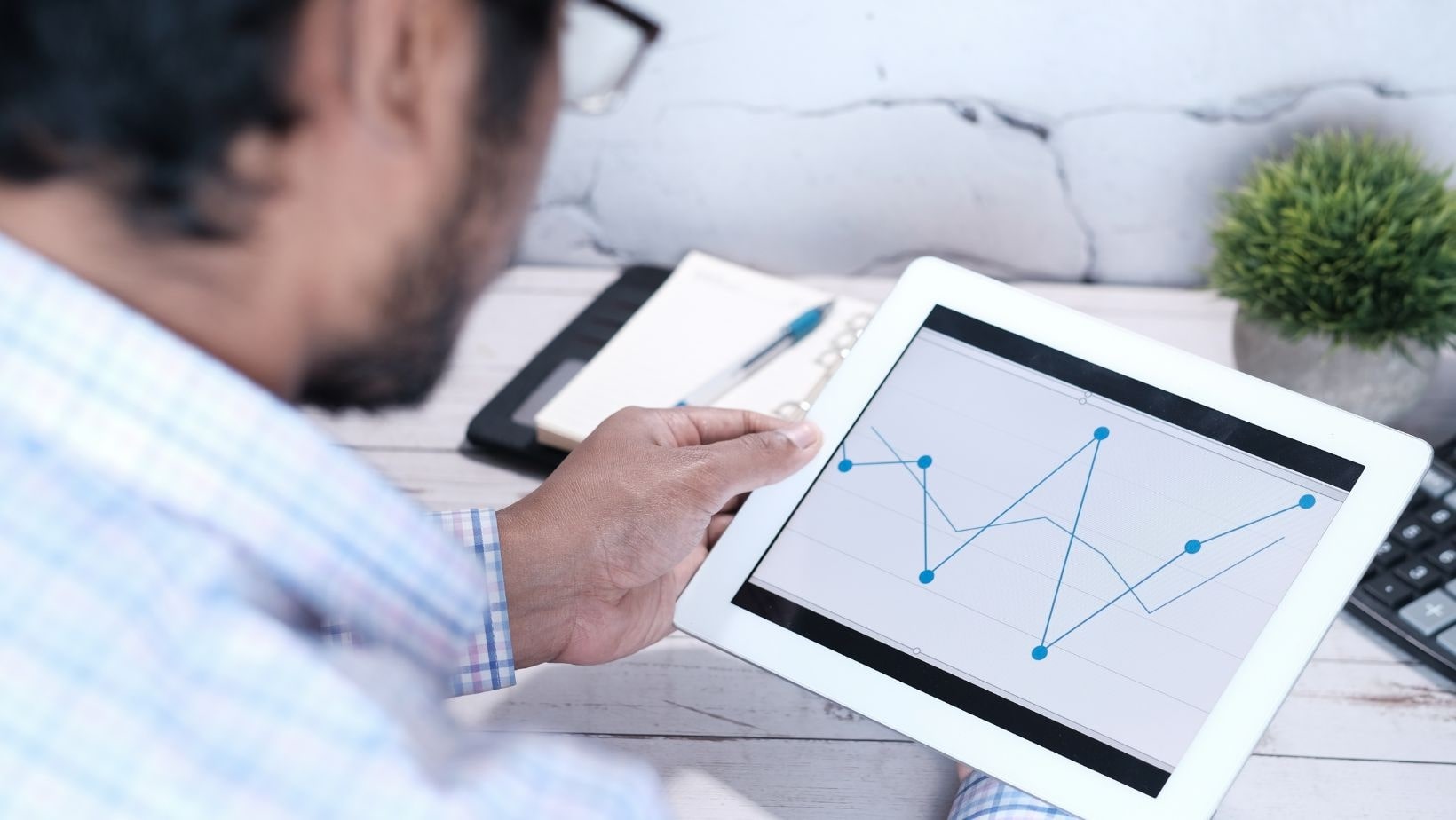 digital platforms and trends man at desk analysing a graph on a tablet