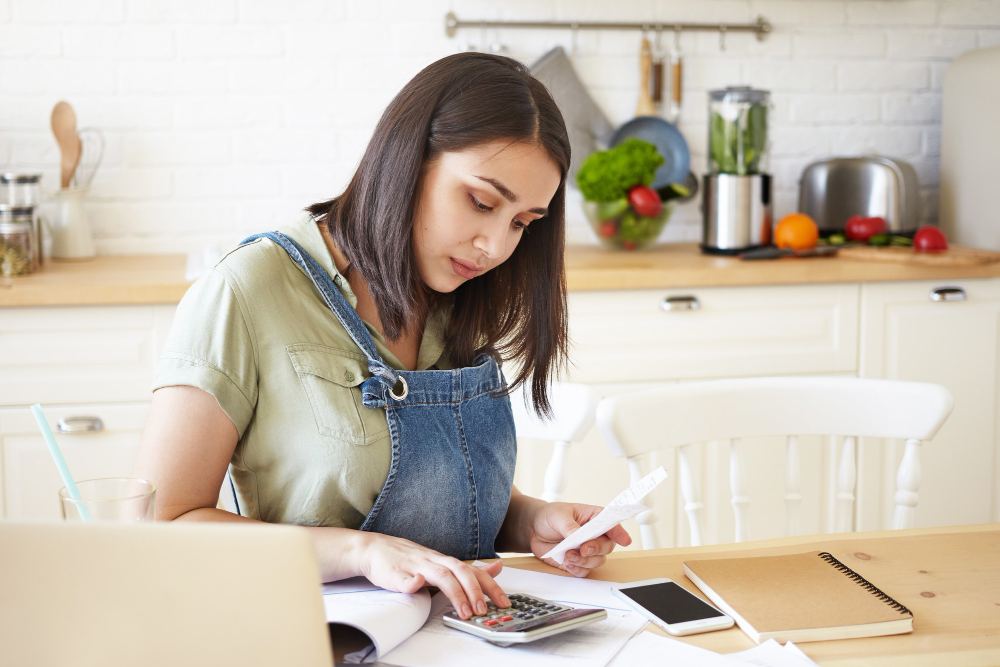 frugal life for saving money- young women sitting in kitchen calculating bills