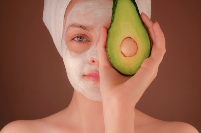  beauty blog niches skincare- women with a beauty mask holding half an avacado pear